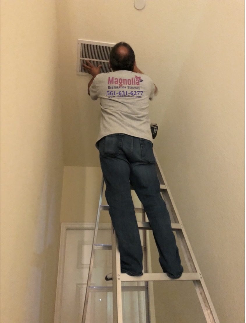 Magnolia technician on a ladder cleaning an air vent