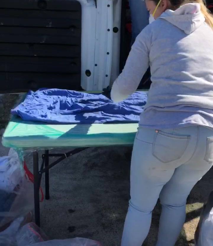 Technician sorting textiles at a folding table beside the work truck